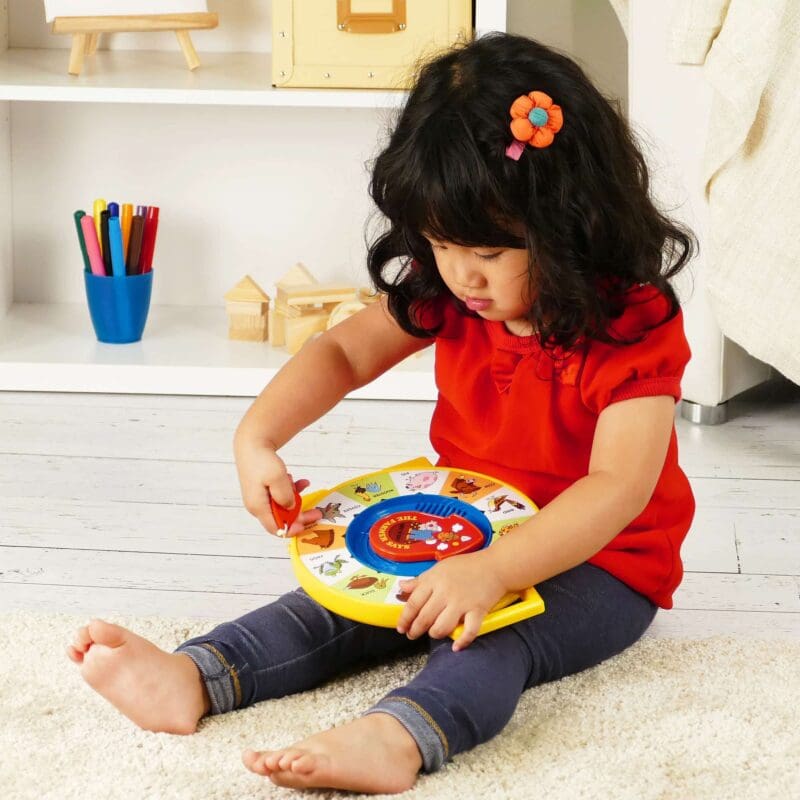 2070-Fisher-Price-See-N-Say-Lifestyle2-web Lifestyle shot of girl sitting on a bedroom floor playing with the Fisher-Price See N Say